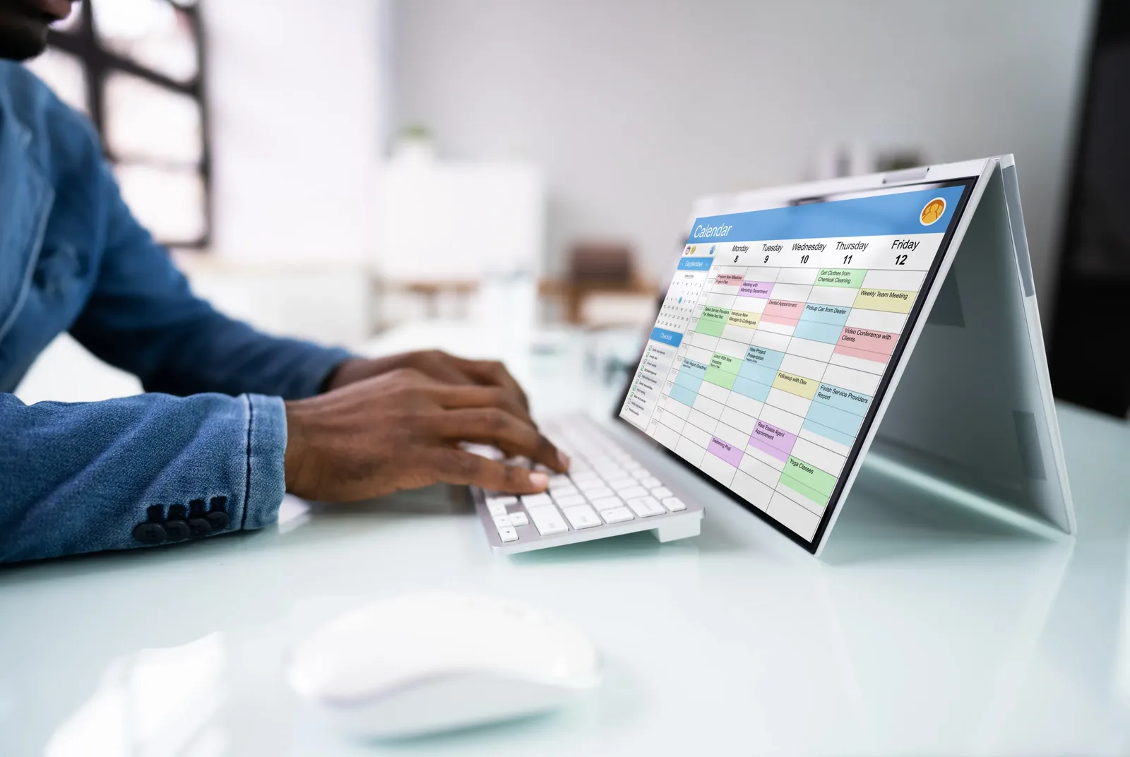 A person working at a laptop showing a full weekly calendar, representing how caffeine habits attach themselves to the structure of a week.